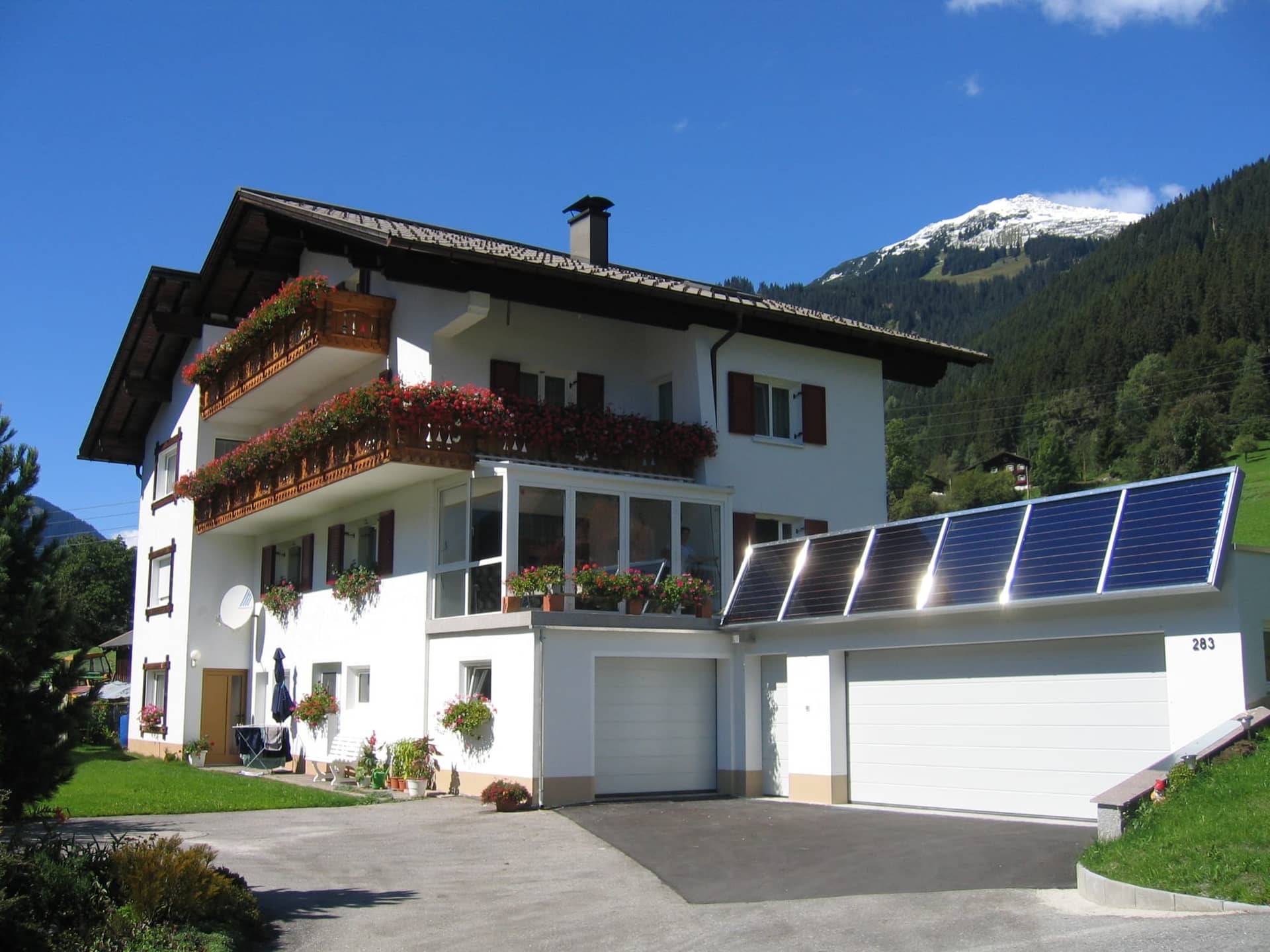 Ferienhaus Lerch im Sommer mit Blumenbalkonen und Bergen im Hintergrund